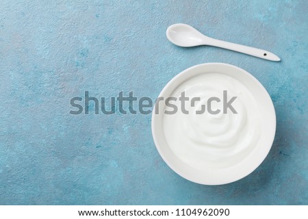 Homemade greek yogurt in bowl on blue stone table top view.