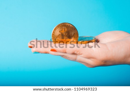 Gold coin bitcoin in a female hand on a blue background