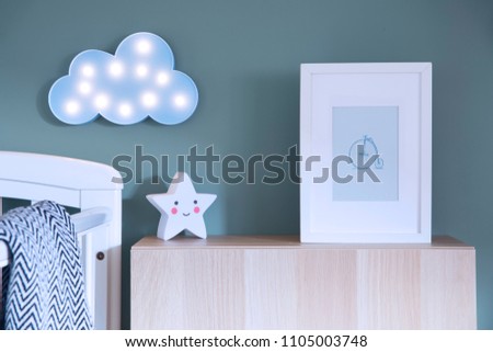 The modern scandinavian newborn baby room with mock up poster frame, blue cloud and star lamp. Sunny and bright interior.