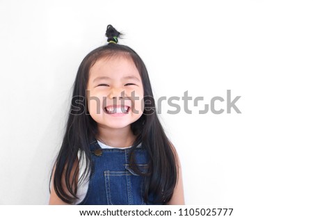 Asian children cute or kid girl and kindergarten student happy smile white teeth and laugh with wear dungarees jean for fashion or child dental on white background with space isolated Royalty-Free Stock Photo #1105025777