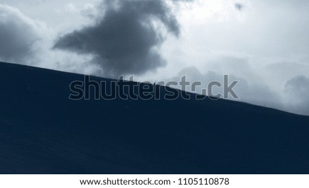 Small skier on big cloudy mountain perspective Royalty-Free Stock Photo #1105110878