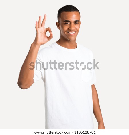 Young african american man showing an ok sign with fingers. Face of happiness and satisfaction on isolated background