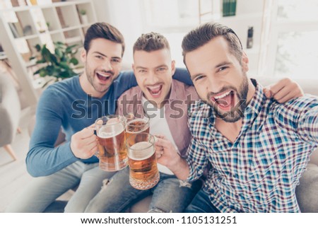 Portrait of stylish, best, attractive, modern positive guys with hairstyle, yelling, sitting on sofa in house, shooting selfie on smart phone, enjoying soccer word cup competition