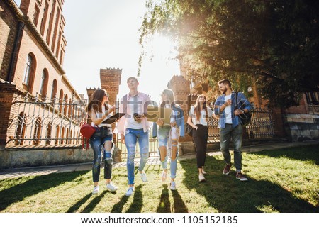 A group of students on campus. Two guys and three girls go to university. They go and laugh. Royalty-Free Stock Photo #1105152185