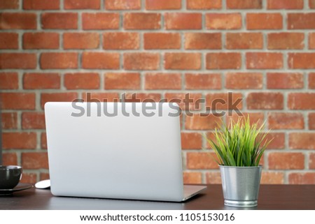 Desk of work table on brick wall background in office with laptop computer , notebook , calculator and a cup of coffee for creative marketing plan to success planning of company