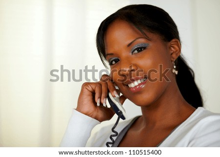 Portrait of a young woman looking at you while talking on phone at soft colors composition