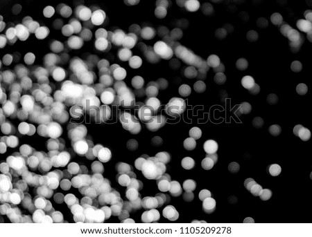 White bokeh on a black background closeup, bright glare of light texture, light lights, black and white photo