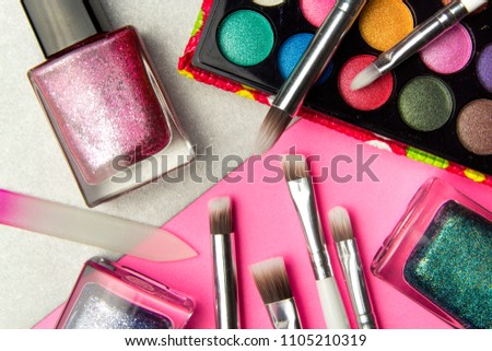 Eyeshadow palette and nail Polish in pink and silver geometric background. Decorative cosmetics for professional makeup. Eyeshadow and nail Polish colors trend.