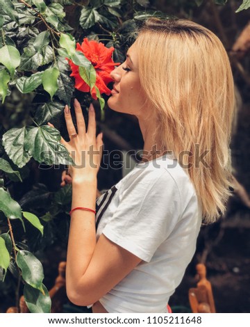 girl sniffs a red flower