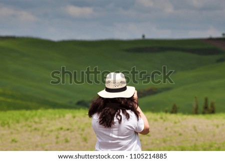 female photographer taking pictures in green summer landscape, tuscany, italy