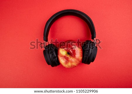 Black Headphones and apple  on red background. Flat lay. Top view. Copy space.