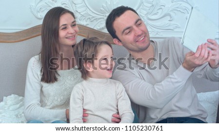 Happy young family taking selfies on sofa with tablet