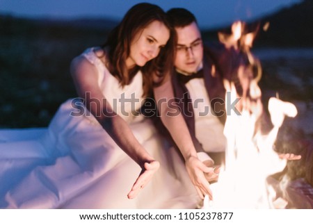 lovers warm their hands near the fire