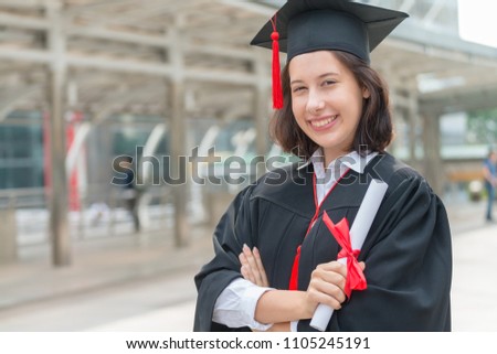 Portrait photo of happy young graduated university student after received certificated diploma. Education and people concept.