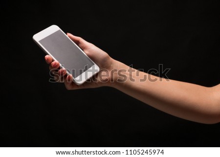 Female hand holding mobile smartphone with blank screen, isolated on black background. Copy space for advertisement of mobile app, mockup