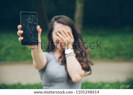 young sad adult woman showing cracked phone