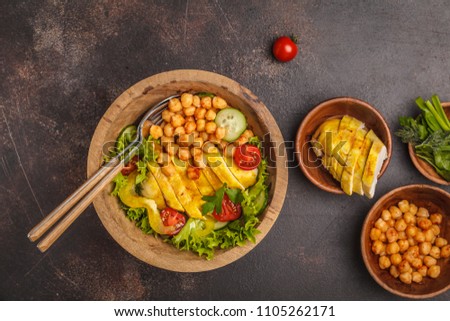 Grilled chicken salad with vegetables and chickpeas in a wooden bowl on a dark background, copy space, top view. Healthy balanced diet concept.