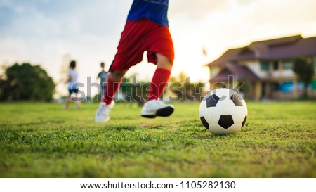 An action sport picture of a group of kid playing soccer football for exercise in community rural area under the sunset. Picture with copy space.