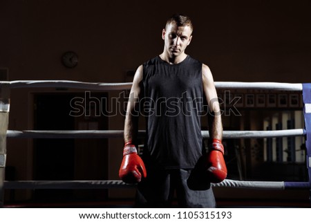 Portrait of a muscular young man in Boxing gloves in the ring.