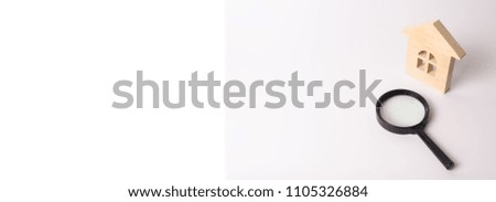 Wooden house and a magnifying glass on a white background. The concept of finding a house, buying or renting an apartment. Realtor services. Search for a new home. Real estate market. Banner