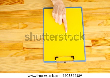 Office Hand Holding a Folder with a Red Color Paper and Pen on the Background of the Wooden Table. Copyspace. Place for Text.