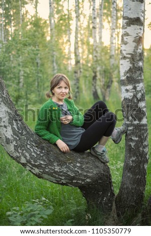 
portrait of a woman in the woods at sunset in casual clothes near a birch tree
