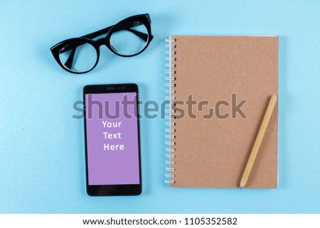 Flatlay notepad with pen near to glasses and smartphone. Space for text.