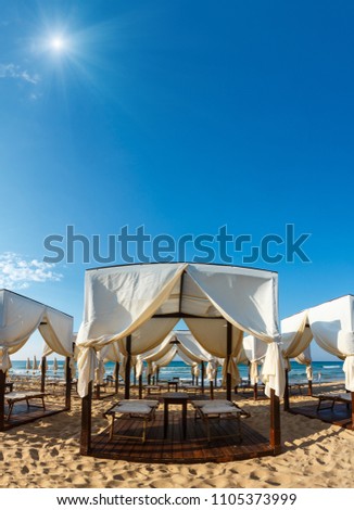 Tents canopies on sunshiny white sandy beach. Two shots stitch image. Beautiful natural summer sea vacation concept.