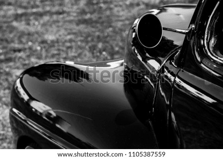 Monochrome picture of vintage car showing a lateral partial view of side and front of vehicle