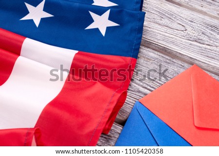 Close up American flag and envelopes. USA national flag and two colorful envelopes on wooden boards.