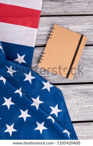American flag and spiral paper notebook. National flag of USA on vintage wooden background. Paper notepad with binder.