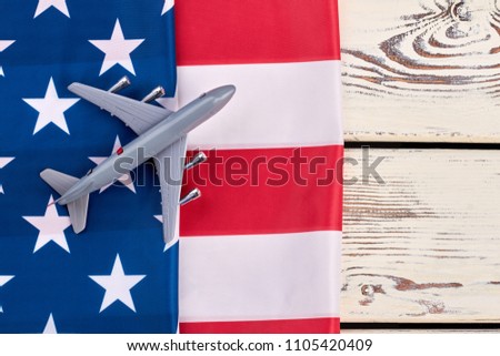 Flag of USA and toy air plane. Plastic toy jet plane and american flag on white wooden background. Flight to America concept.