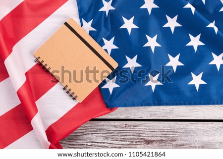 Flag of USA, notepad and copy space. American patriotic flag and paper notebook on wooden background.