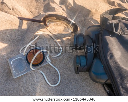 travel searching concept, compass binoculars and magnifier on the sand
