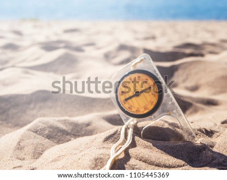old compass buried in sand on a sea coast beach