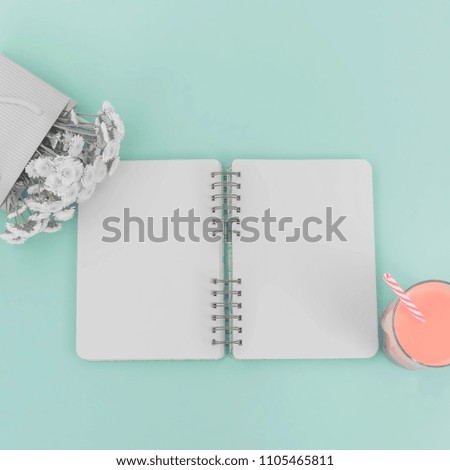 Open notebook for records lies on the surface of the cocktail pink glass tube bouquet of chrysanthemums. The pastel green background copy space
