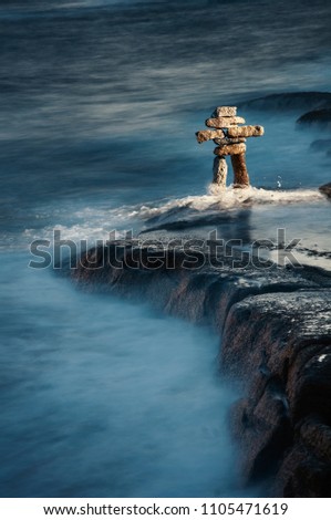 Inukshuk on the Atlantic shore with waves washing over at night.