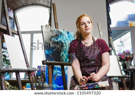 Portrait of a young female artist with brushes for painting.