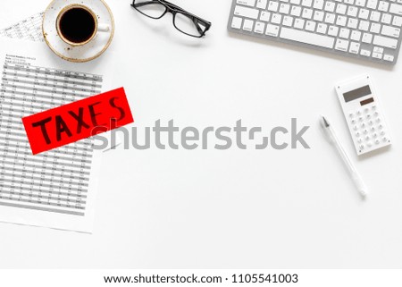 Pay taxes concept. Taxes word on office work desk with keyboard and calculator on white background top view space for text