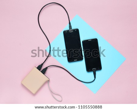 Power bank charged two smartphones on a colored pastel background. Modern gadgets. Top view. Minimalism
