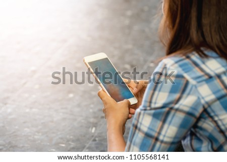 Woman wearing plaid shirt sit on floor using and checking smart phone,Mockup image of a lady  excessively sitting on the street and holding mobile phone,she is a victim of online social networks,