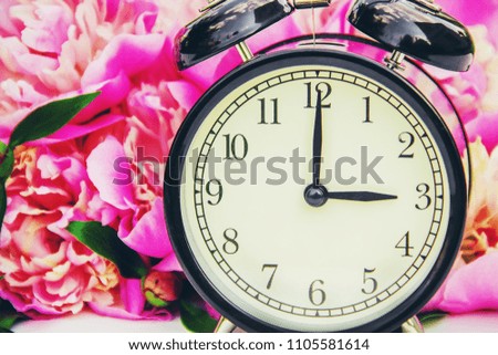 Spring flowers and Alarm Clock. Change the time. Selective focus.