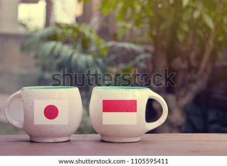 Japan and Indonesia Flag on two tea cups with blurry background