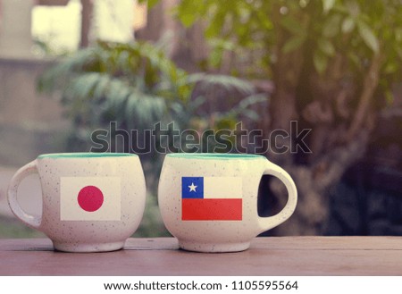 Japan and Chile Flag on two tea cups with blurry background