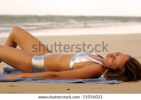 Woman in silver bikinis sunbathing on the beach