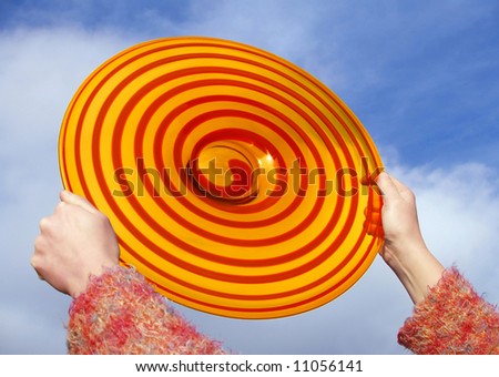 Red the and orange disc in the girl's palms on background of blue sky