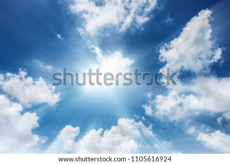 White clouds and bright blue sky background and sunburst