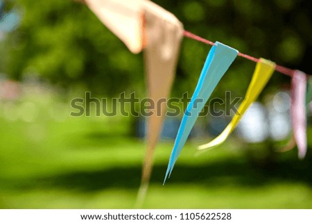 Blurred background. Multicolored triangular paper festival flags in the park. Outdoor Celebration Party. Festive mood