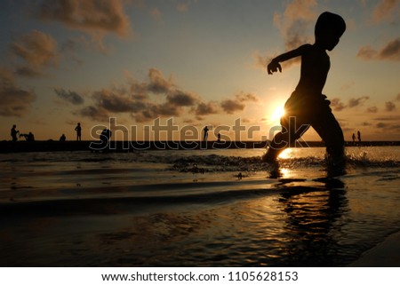 Happy children silhouettes on parangtritis beach running and jumping