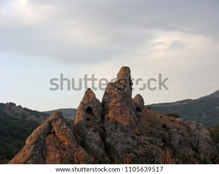 Mountain landscape. Beautiful natural landscape in the mountains. Unusual mountain peaks with caves at sunset on a Sunny summer day against the sunset sky and mountains in the distance